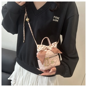 Detail of pink quilted mini bucket bag with camellia charm and bow accent on model