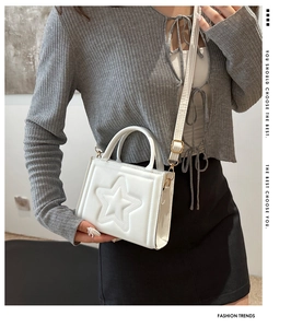 Detailed view of a white square handbag with 3D star pattern and gold hardware