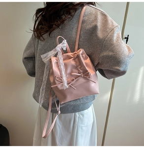 Mini zaino in pelle rosa con fiocchi e pizzo, vista posteriore indossata da modella