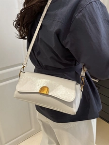 Sac baguette rétro blanc avec boucle dorée porté à l'épaule pour un style français chic