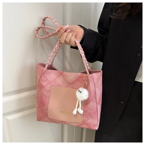 Dettaglio della borsa tote rosa con logo fashion, manici intrecciati e charm peluche