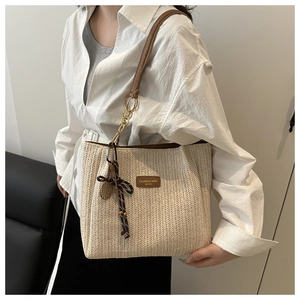 Dettaglio borsa tote in paglia con logo in pelle marrone e nastro decorativo a scacchi