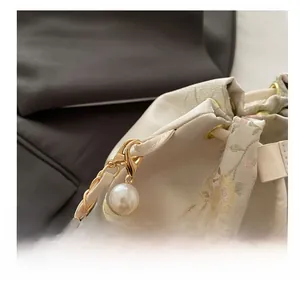 Detailed macro view of golden lobster clasp and pearls on the floral embroidered bucket bag