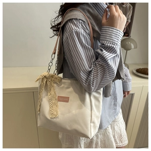 Détail du sac cabas crème avec bandoulière en cuir rose et nœud en dentelle