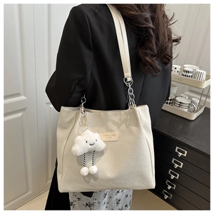 Detail of corduroy tote bag with leather strap, metal chain and plush cloud charm