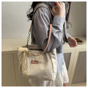 Close-up of cream tote bag with pink straps, lace bow, and Fashion & Bags leather label