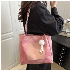 Detailed macro of pink quilted tote bag with braided handle and plush mascot charm