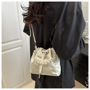 Detail of champagne satin bucket bag with floral embroidery and large pearl handle