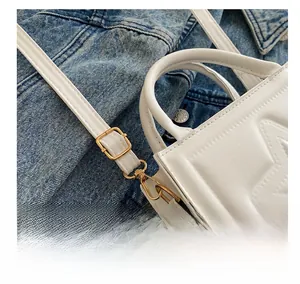 Detail showing adjustable golden metal buckle on white star embossed crossbody bag