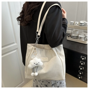 Detail of off-white canvas tote bag with diagonal texture and cute plush cloud charm