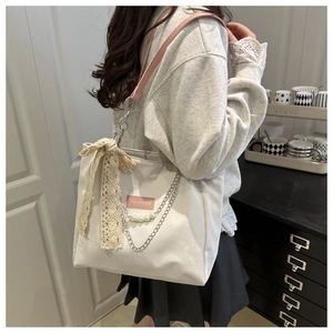 Détail du cabas blanc avec nœud en dentelle, chaîne perlée et doubles lanières