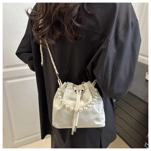 Detail of satin bucket bag with floral embroidery and pearl handle worn by a model
