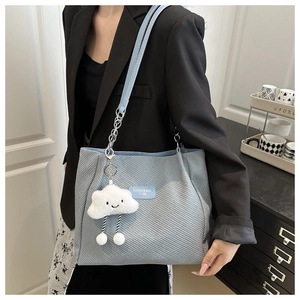 Close-up of light blue woven tote bag with chain strap and plush cloud charm detail