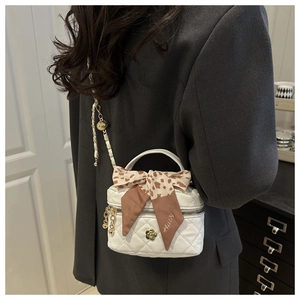 Detail of white quilted mini bag with gold flower clasp and leopard print silk scarf