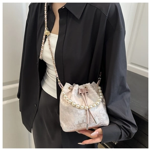 Detail of champagne pink satin bucket bag with floral embroidery and pearl handle