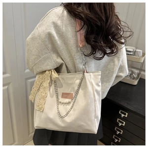 Detail of cream tote bag with pink straps, lace bows and pearl chain decoration