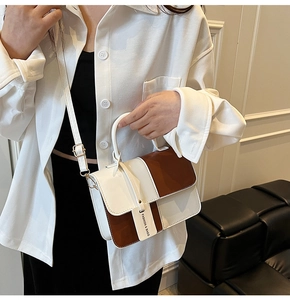 Detail of minimalist contrast-color handbag with single handle and adjustable strap