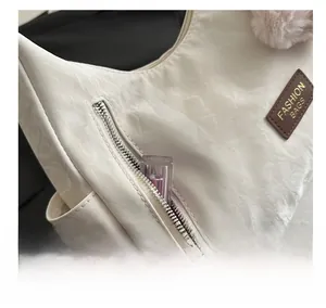 Dettaglio borsa beige con trama a pieghe e pratica tasca laterale con cerniera