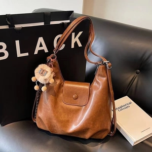 Detail of dark brown vintage faux leather tote bag with cute lion plush keychain
