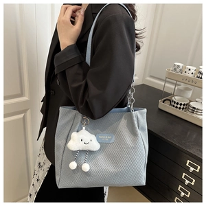 Detail of light blue tote bag featuring textured fabric and cute cloud plush charm