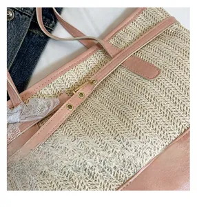 Close-up of straw tote bag showing pink leather straps and elegant lace bow detail