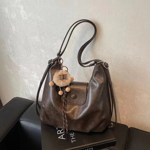 Detail of vintage brown hobo bag with soft faux leather texture and lion plush charm