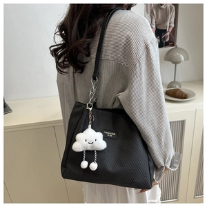 Detail of black twill canvas tote bag featuring a cute white plush cloud charm and silver chain