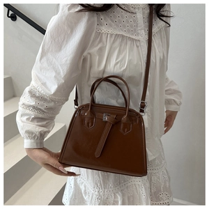 Brown structured retro handbag styled with a white lace dress in a minimalist setting