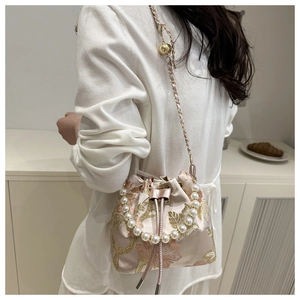 Detail of pink embroidered bucket bag with pearl handle and silk-like floral texture