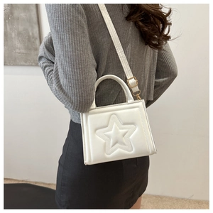 Detail of white star embossed handbag showing crossbody strap and fine leather texture