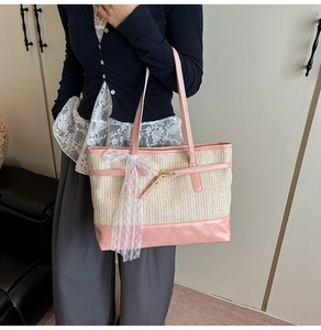 Detail of a woven straw tote bag with pink leather trim and white lace bow decoration