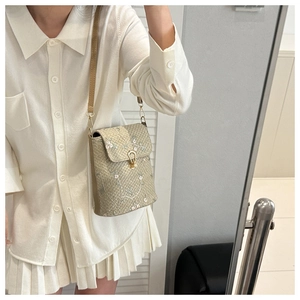Détail du sac bandoulière en paille tressée avec broderie florale blanche et fermoir doré