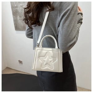 White shoulder bag featuring 3D star embossed design shown on a model for scale