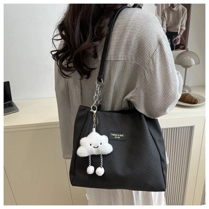 Detail of black corduroy tote bag featuring leather chain strap and cloud plush charm