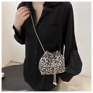 Detail of leopard print bucket bag with silver chain strap worn over a black shirt