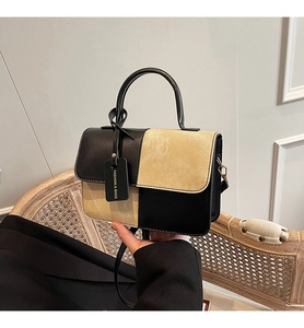 Detail of two-tone contrast bag featuring black smooth and beige suede拼接 texture