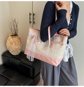 Macro detail of the woven straw tote bag with pink leather trim and white lace bow