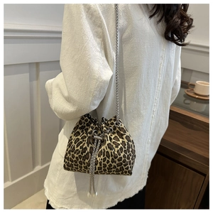 Detail view of leopard print bucket bag with metal chain strap on white blazer