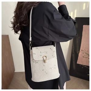 Sac bandoulière chic en paille avec broderies florales et fermoir doré sur tenue noire