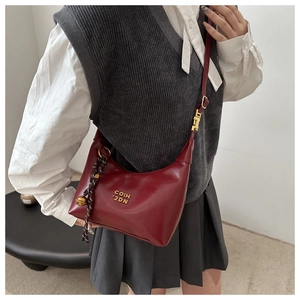 Sac à main bordeaux chic en cuir avec logo doré et charm clochette sur modèle