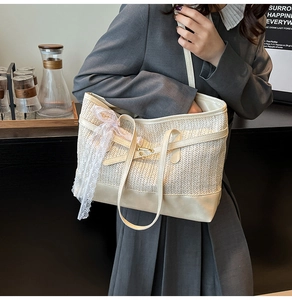 Detail of white straw tote bag featuring delicate lace bow and beige leather trim