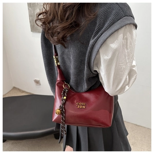 Détail du sac hobo bordeaux avec logo doré et breloque clochette sur le mannequin