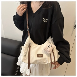 Dettaglio della borsa tote in tela bianca con inserti in pelle marrone e charm orsetto