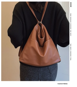 Detailed back view of a large brown leather backpack worn by a model against a neutral wall