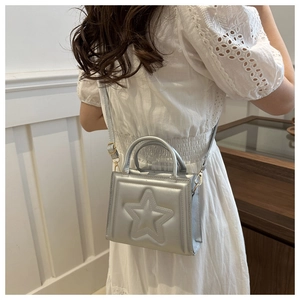 Detail of silver small square bag featuring embossed star pattern and gold metal hardware