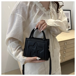Detail of black crossbody bag with embossed star pattern carried by a model