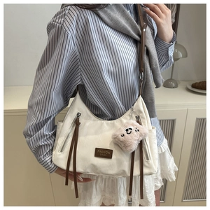 Dettaglio borsa tote bianco crema con cinturini in pelle e ciondolo rosa