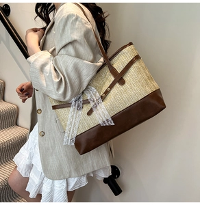 Close-up of woven straw tote bag featuring brown faux leather straps and lace bows