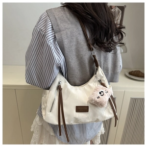 Borsa hobo bianca con cinturini marroni e ciondolo di peluche indossata da modella