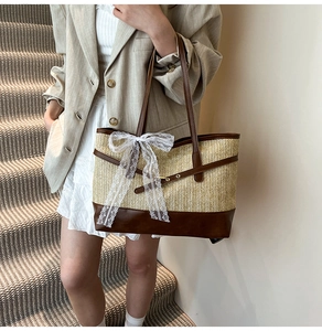 Detail of a straw tote bag featuring a white lace bow and brown leather trim accents